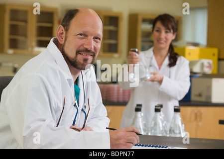 Wissenschaftler mit Laborantin im Hintergrund Stockfoto