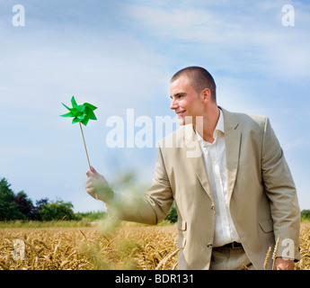 Geschäftsmann mit einer Windmühle in einem Roggenfeld Stockfoto