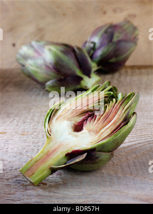 Die Side Shot frische Artischocken (Cynara Cardunculus) gegen einen Holz Hintergrund Stockfoto