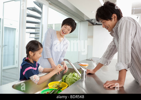 Eltern und Tochter in der Küche stehen Stockfoto