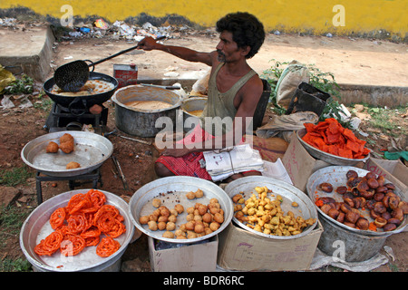 Indischer Mann Braten Samosas und Doughballs In einem Orissan Markt Stockfoto