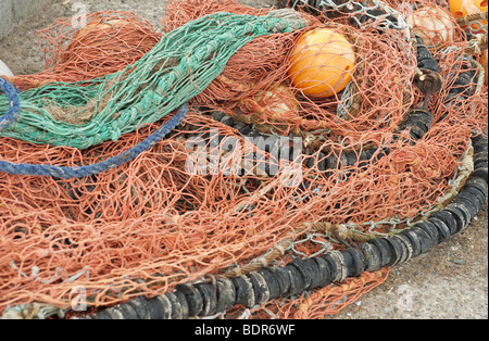 Nahaufnahme von leuchtend orange Meer Fischernetze mit angehängten Schwimmern gestapelt auf einem Hafen am Hafen Stockfoto