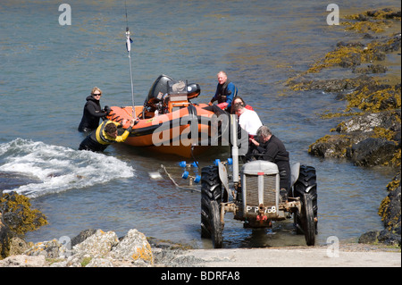 Mit einem Traktor ein Boot aus dem Meer auf einer Hangbahn in Wales ziehen. Stockfoto