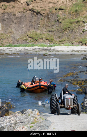 Mit Hilfe eines Traktors, ein Boot aus dem Meer auf eine Slipanlage in Wales zu schleppen Stockfoto