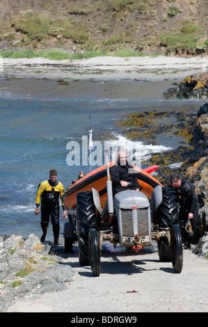 Mit Hilfe eines Traktors, ein Boot aus dem Meer auf eine Slipanlage in Wales zu schleppen Stockfoto