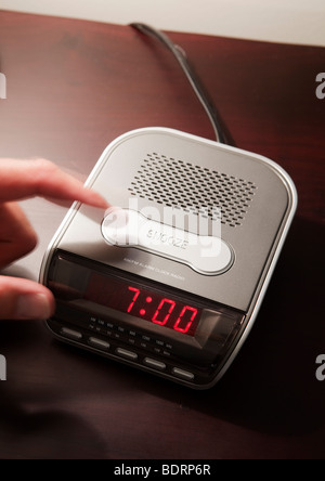 Finger drehen der Wecker auf 07:00 Drücken der Snooze-Taste. Stockfoto