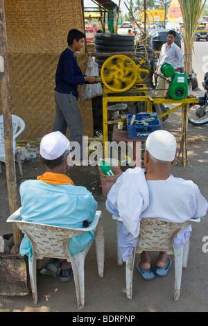 Muslimische Männer warten auf ihren frisch gepressten Zuckerrohrsaft in Daulatabad nahe Aurangabad, Indien Stockfoto