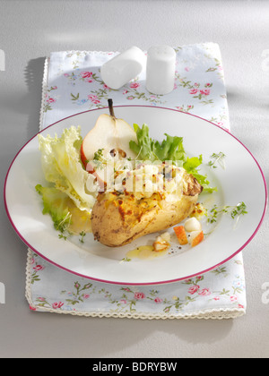 Kartoffelgratin mit Birne und Salat auf einem Teller mit einem floral Serviette und Salz- und Pfefferstreuer Stockfoto