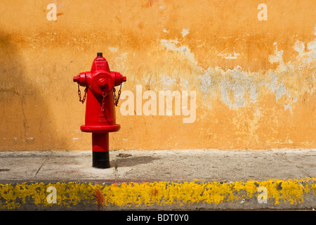 Red Fire Hydrant an alten verblichenen Wand Stockfoto