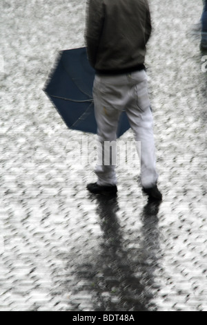 junger Mann mit Regenschirm bei starkem Regen in der Stadt Stadt Stockfoto