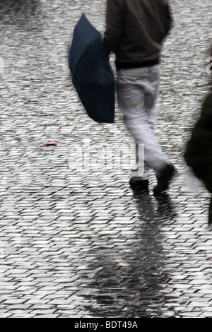 junger Mann mit Regenschirm bei starkem Regen in der Stadt Stadt Stockfoto