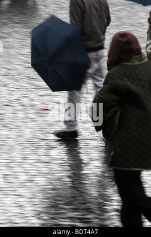junger Mann mit Regenschirm bei starkem Regen in der Stadt Stadt Stockfoto
