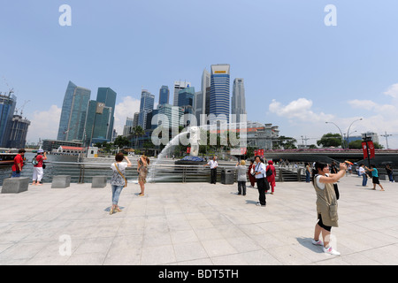 Touristen fotografieren vor der Merlion mit Skyline der Stadt hinter Singapur Stockfoto