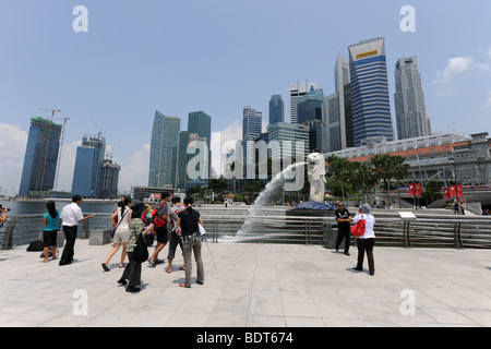 Touristen fotografieren vor der Merlion mit Skyline der Stadt hinter Singapur Stockfoto