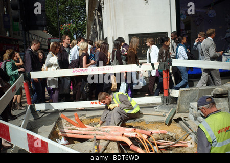 Arbeiter ersetzen, Rohre und Kabel stören den freien Verkehr von Fußgängern Oxford Street London Stockfoto