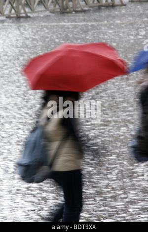 Person mit Regenschirm bei starkem Regen in der Stadt Stockfoto