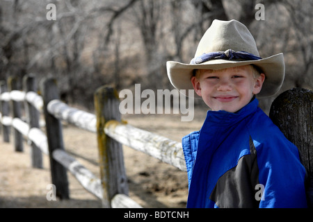 Junger Cowboy - lächelnde junge in West- oder Cowboy-Hut auf Ranch Zaun entlang. Stockfoto