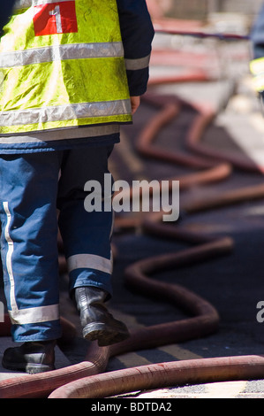 Ein Feuerwehrmann Schritte über Schläuche während der Zeit nach dem 30. April 2007 Dale Street-Feuer in Manchester, England. Stockfoto