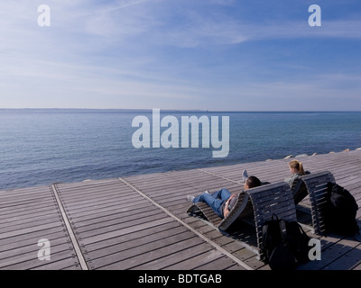 Zwei junge Menschen entspannen Sie auf der Promenade Liegestühlen mit Blick auf den Öresund in Helsingborg, Schweden. Stockfoto