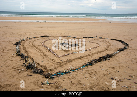 Herzförmiges Muster aus Algen und Steinen; Strandkunst und Sanddünen Küstenlandschaft in Fraserburgh Bay, Aberdeenshire, Schottland, Großbritannien. Stockfoto