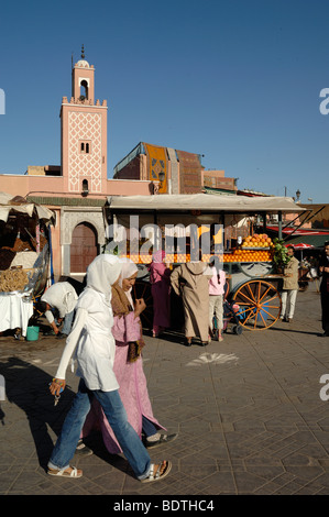 Marokkanische Mädchen tragen Schals Spaziergang vorbei an einem Orangensaft Stall auf Djemaa El-Fna Platz Djemaa El Fna Marrakesch Marokko Stockfoto