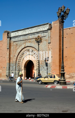 Ein marokkanischer Mann mit traditionellem Djellaba oder Jellaba geht am Bab Agnaou Tor (1188-1190) in der Stadt oder Stadtmauer von Marrakesch, Marokko vorbei Stockfoto