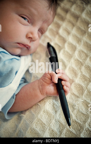 Neugeborenes Kind hält einen Stift Stockfoto