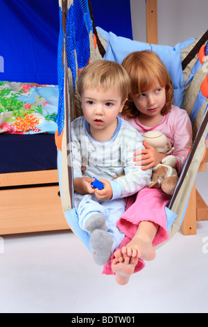 kleine Mädchen und jungen in einem Schwung ein Billi-Bolli Hochbett Stockfoto