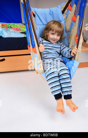 kleiner Junge im Pyjama in einem Schwung ein Billi-Bolli Hochbett Stockfoto