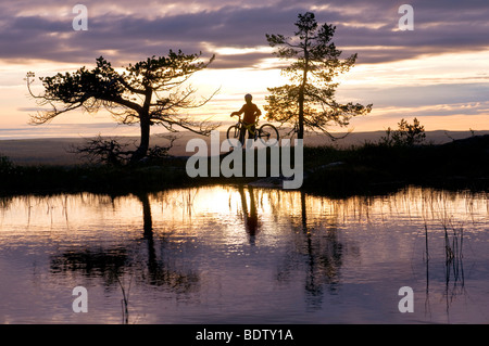 Mountainbikerin ein Einem Bergsee in Lappland, Schweden, Gaellivare, Abfahrt Radfahrer an einem Bergsee in Lappland, Schweden Stockfoto