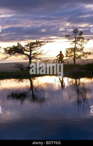 Mountainbikerin ein Einem Bergsee in Lappland, Schweden, Gaellivare, Abfahrt Radfahrer an einem Bergsee in Lappland, Schweden Stockfoto