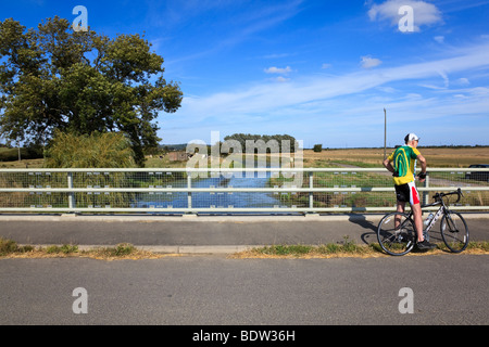 Ein älterer Radfahrer ruht auf einer Brücke über die Royal Military Canal auf dem Saxon Shore Weg, in der Nähe von Ruckinge, Kent, Großbritannien Stockfoto