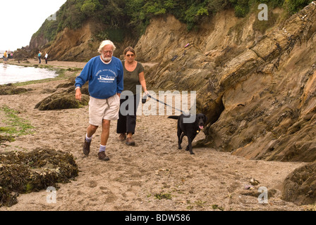 Ein Ehepaar im Ruhestand zu Fuß ihre Labrador auf Mothecombe Strand Stockfoto