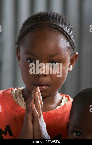 Kenia steht der Kongregation in der katholischen Messe in Mukuru Ruben, einem Slum von Nairobi. Kinder beten Stockfoto
