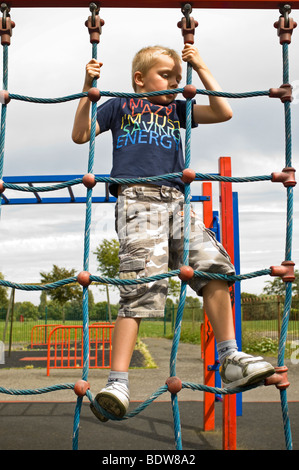 Vertikale Nahaufnahme Portrait eines jungen Mannes mit viel Spaß ein Gepäcknetz Klettern auf einem Klettergerüst in ein Spielplatz Stockfoto