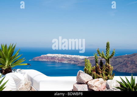 Pflanzen und Kakteen auf Felsvorsprung mit Blick auf Caldera und die Mittelmeer-Aussicht von Oia auf der griechischen Insel santorini Stockfoto