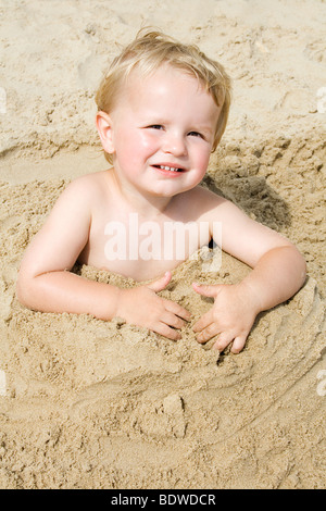 junge vergraben im Sand bis Taille Stockfoto