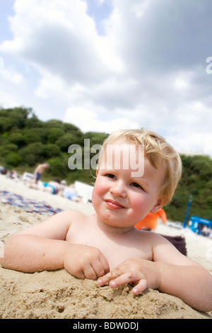 Boy am Strand bis zur Taille im Sand begraben Stockfoto