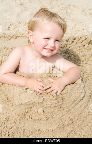 junge vergraben im Sand bis Taille Stockfoto