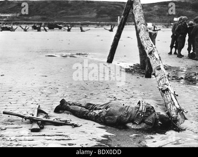 6. Juni 1944 - tritt tot uns Soldaten am Omaha Beach als Gezeiten auszusetzen deutschen Abwehrkräfte. Beachten Sie gekreuzte Gewehre zu Ehren. Stockfoto