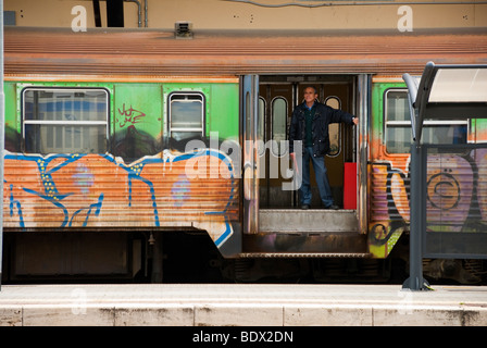 Mann bedeckt stehend in offenen Tür auf einem Graffiti Regionalzug im Bahnhof Arezzo Italien Stockfoto