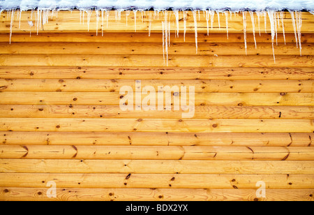 Eiszapfen hängen vom Dach Holz Blockwand Stockfoto