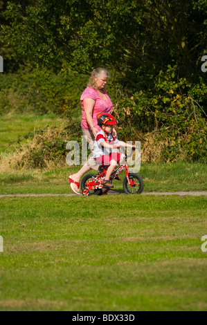 Frau und ein kleines Kind auf ein kleines Fahrrad zu Fuß auf dem Lande Stockfoto