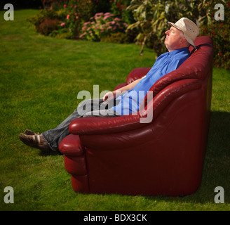 Mann sitzt auf einem Sofa im Garten. Stockfoto