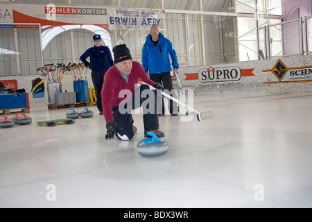 Besucher auf Schweizer Dorf versuchen Eisstockschießen am lokalen Eisbahn. Stockfoto