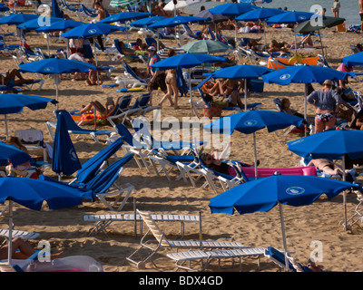 Touristen mit Sonnenliegen und Sonnenschirme am Strand von Fig Tree Bay, im Dorf von Protaras, Zypern. Stockfoto