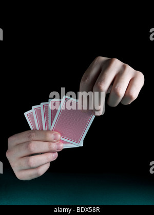 Eines Mannes Hand mit fünf Karten über einen grünen Filz. Stockfoto