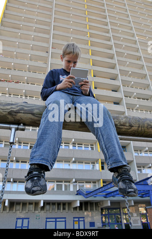 Junge, Sat 9, spielt mit seinem Nintendo vor einem Hochhaus Wohnung Stadt Chorweiler in Köln Nord Rh Stockfoto