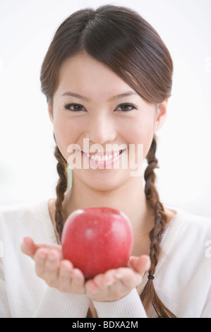 Junge Frau hält einen roten Apfel, Porträt Stockfoto