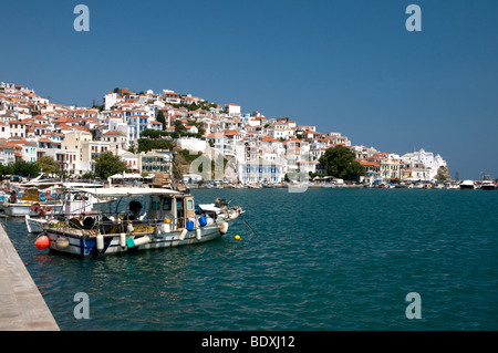 Der Hafen von Skopelos auf der griechischen Ferieninsel Skopelos wurde von einem geschwungenen Kai um den Hafen mit der Altstadt auf dem Hügel dahinter, Griechenland, Europa, aufgenommen Stockfoto